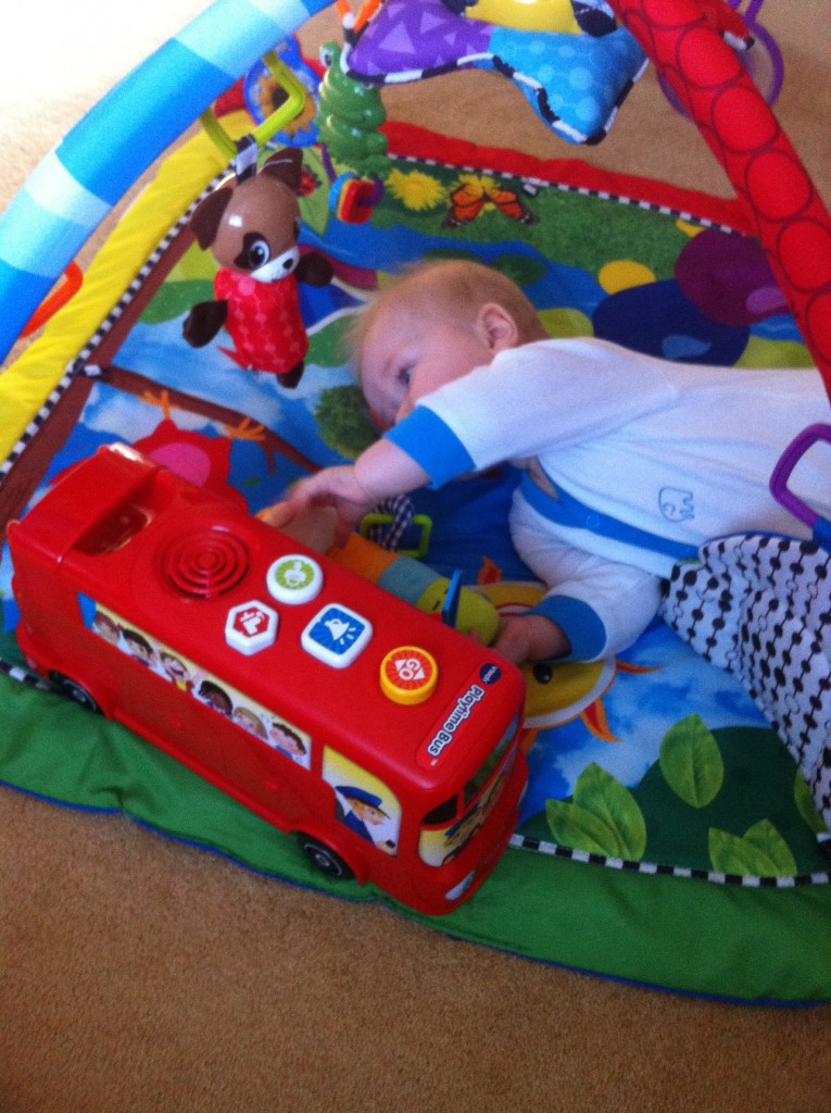Vtech Playtime Bus with Phonics Review. Lucas is lying on his playmat playing with the bus