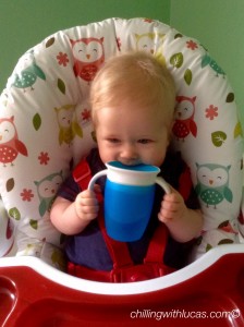 Lucas biting on the blue munchkin cup