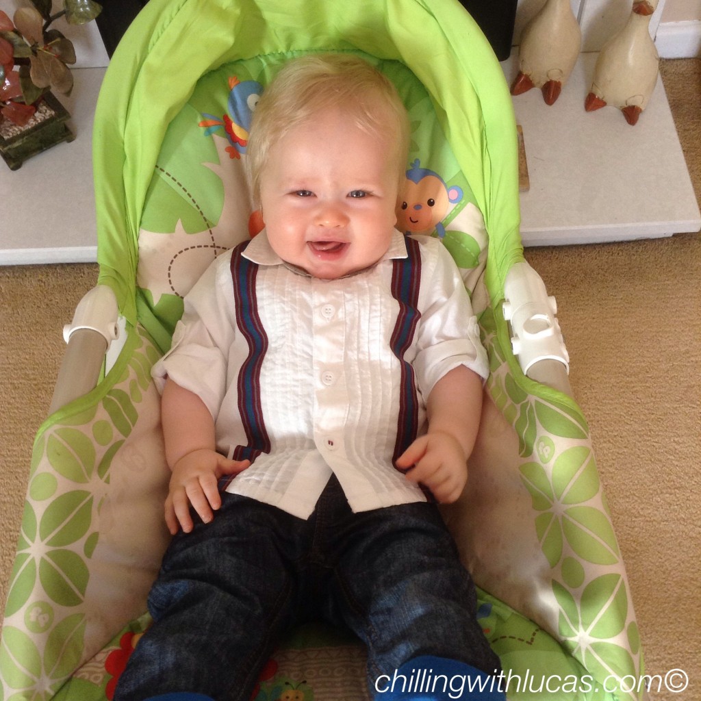 Lucas in his chair samiling at the camera wearing a white shirt with blue jeans