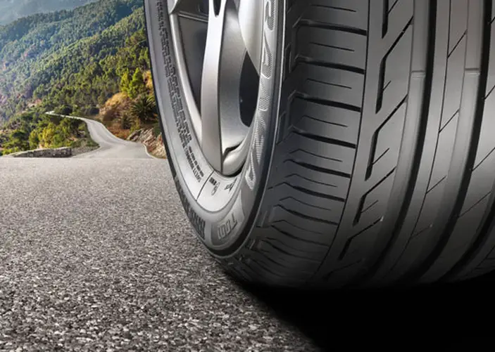 a close up of a tyre with a country road behind