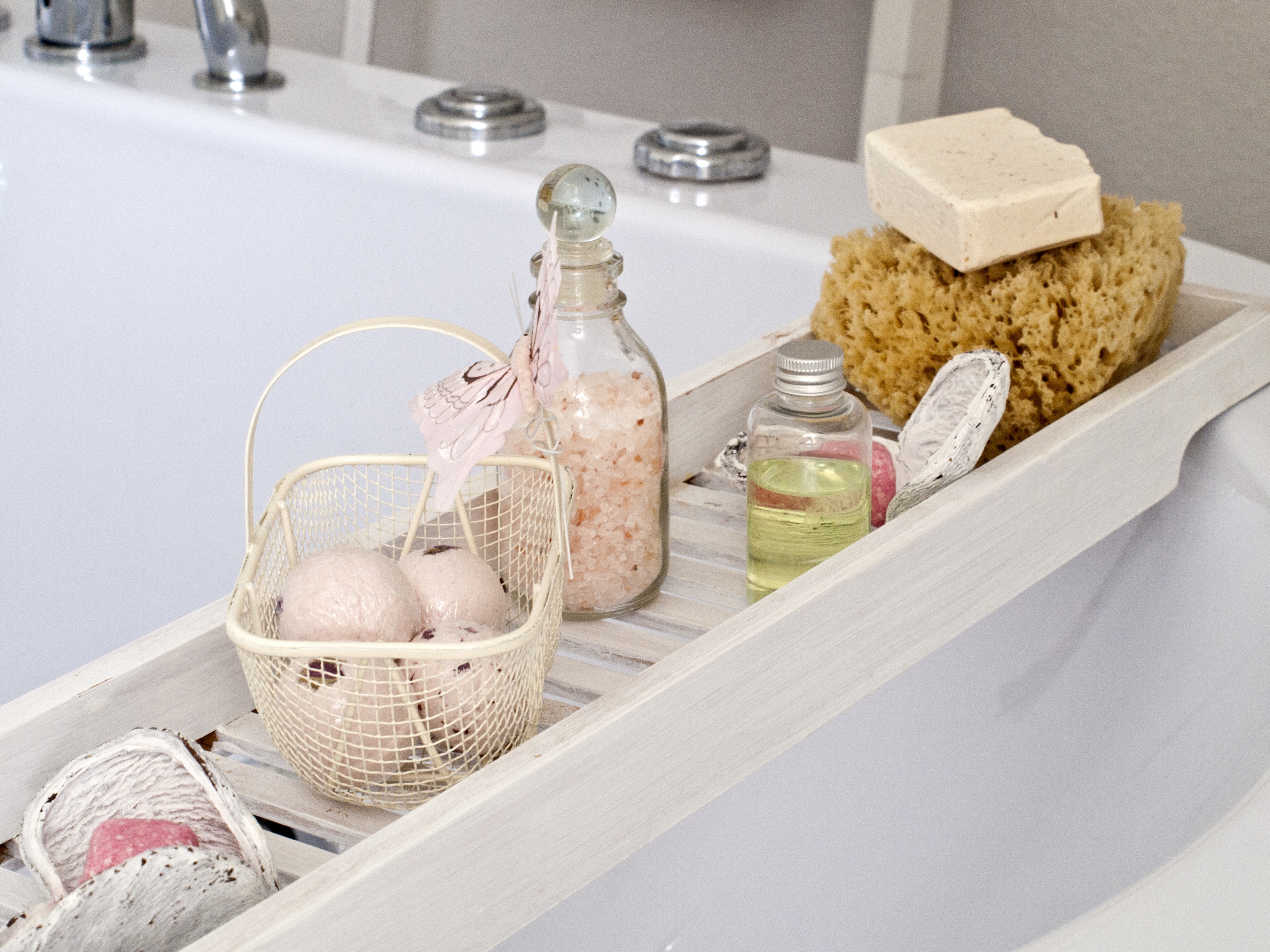 Parents relax around the home. A photo of a bath with bath bombs and bottles of bath oil. A relaxing neutral scene