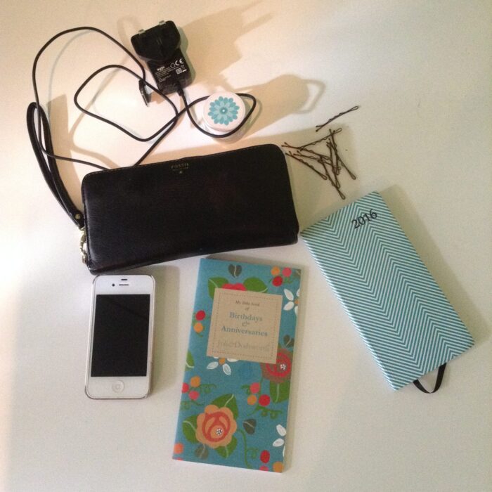 Blogtober, what's in my bag. Photo of white iPhone 4, julie Dodsworth floral birthday book, white and green stripy diary, black phone charger, brown kirby grips, black leather fossil purse, lip balm