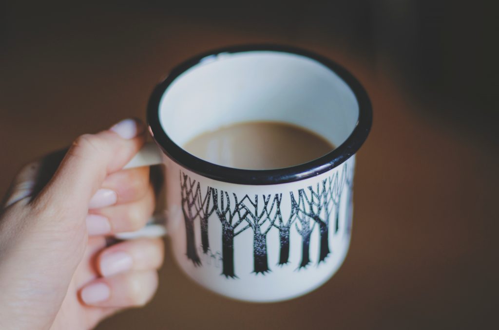 what mummy really wants for christmas. a cup of coffee. white mug with black trees on it filled with coffee being held 
