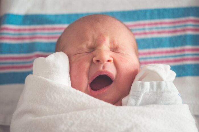 Baby constipation baby feeding issues. A baby wrapped up in swaddle style yawning