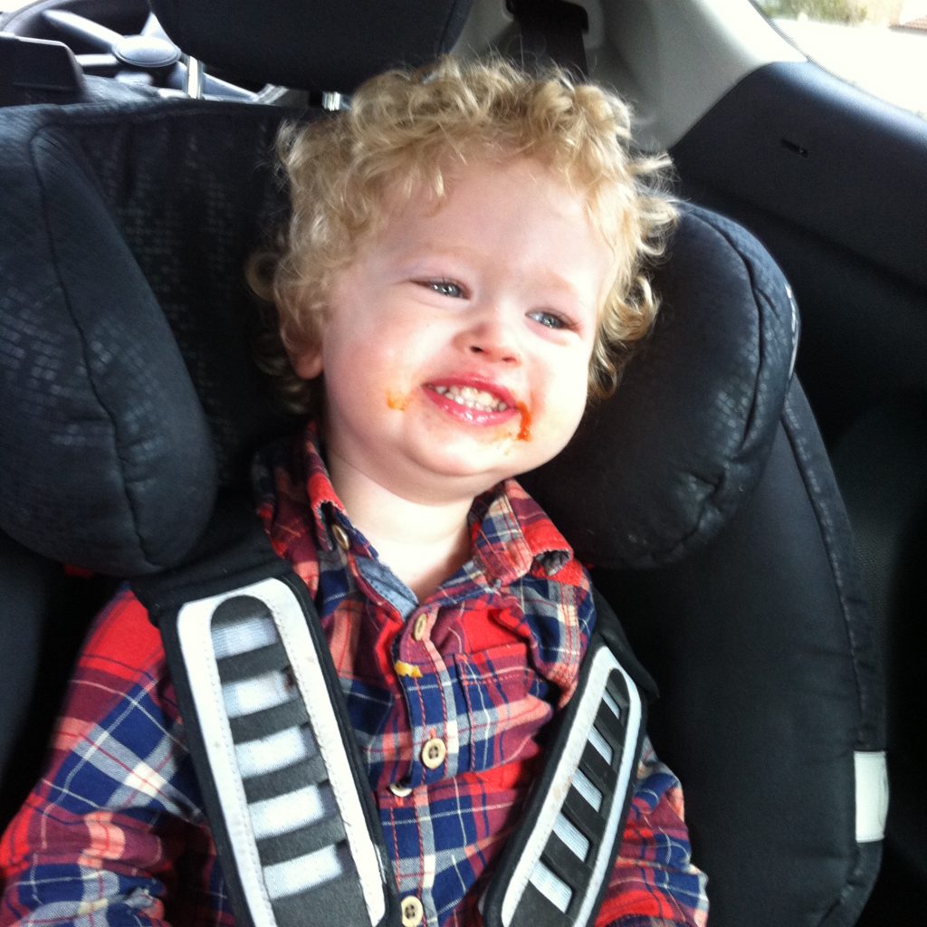 The ordinary moments. Lucas sat in his car seat with a huge teethy smile, tomato ketchup around his mouth. Red and blue checked shirt, blonde curly hair 