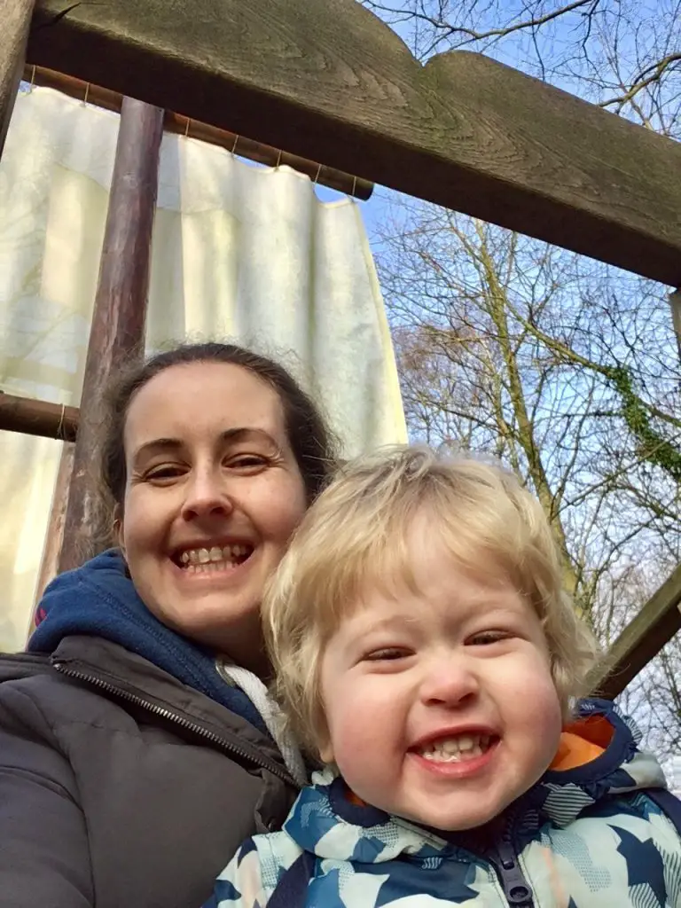 Samlesbury Hall, Preston. Lucas and I smiling into the camera with a pirate sail behind us. I have dark hair tied up wearing a blue hoody and grey coat. Lucas is sat in front of me blonde hair