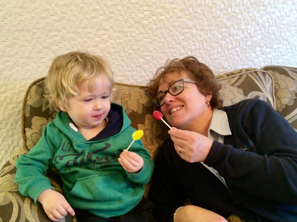 Zollipops a photo of my mum and Lucas sat on the sofa, they both have a lolly in their hand. 