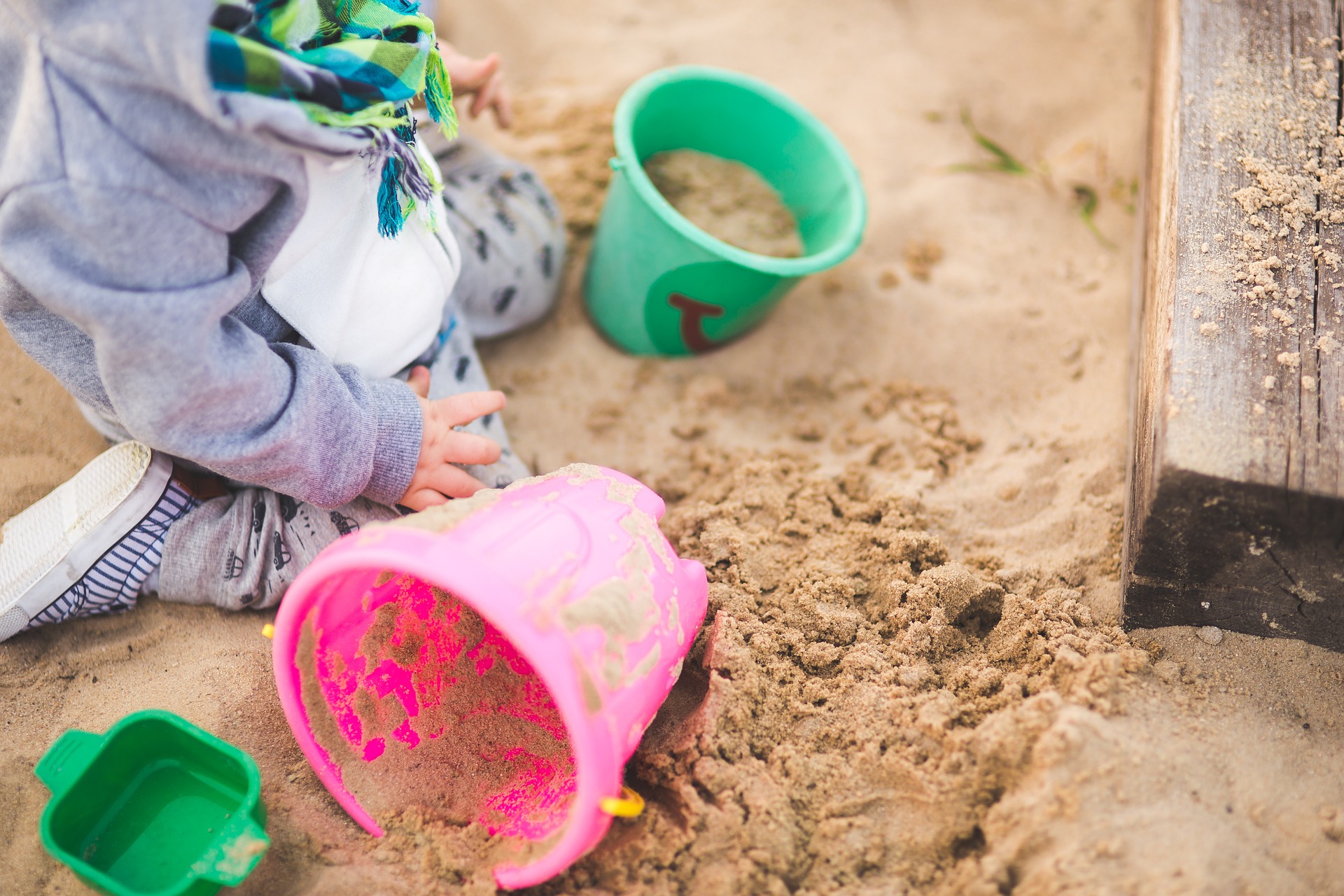 The best toys to get children outside sand with a child kneeling and two buckets
