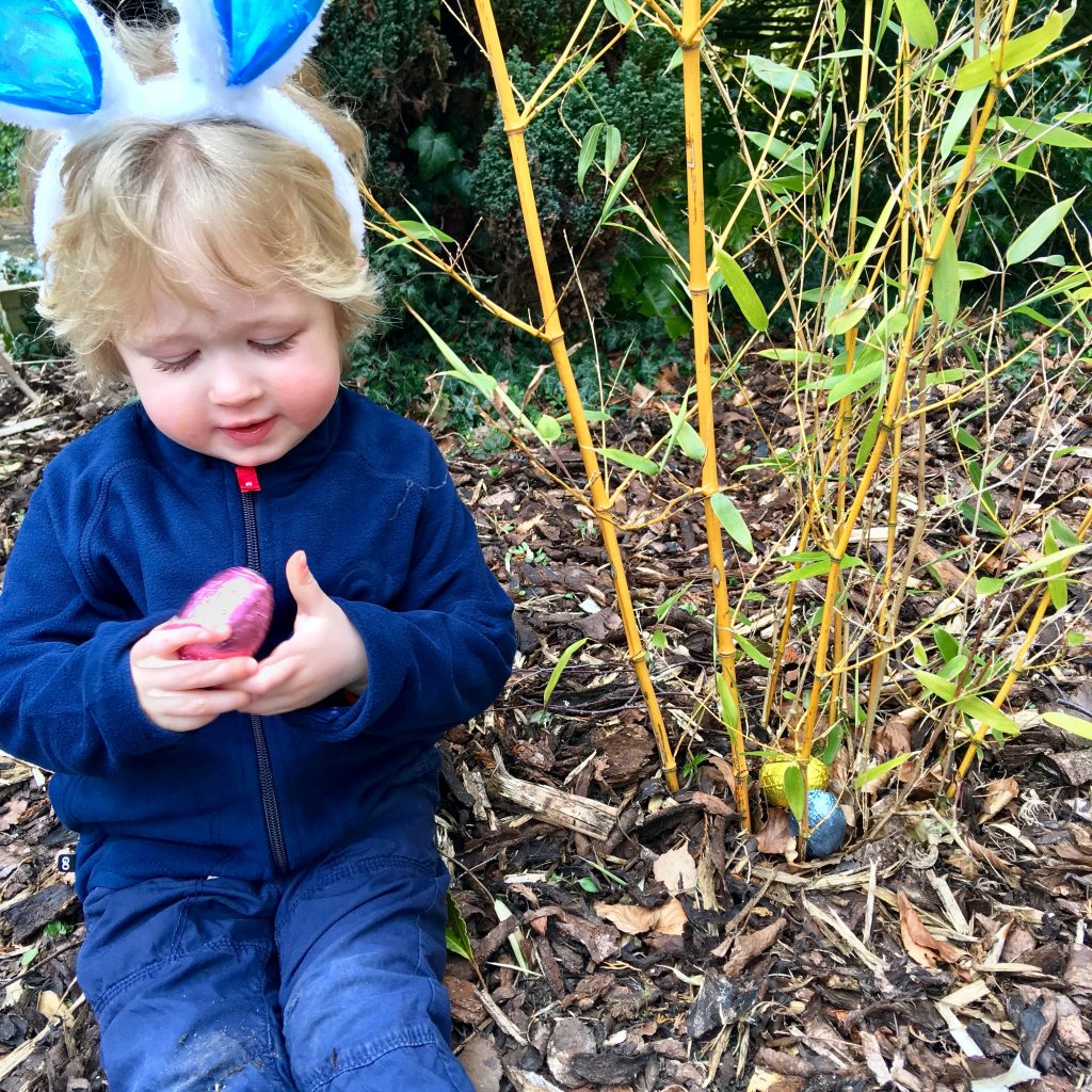 Easter egg hunt, Lucas is sat looking at the pink foiled egg he has just picked up