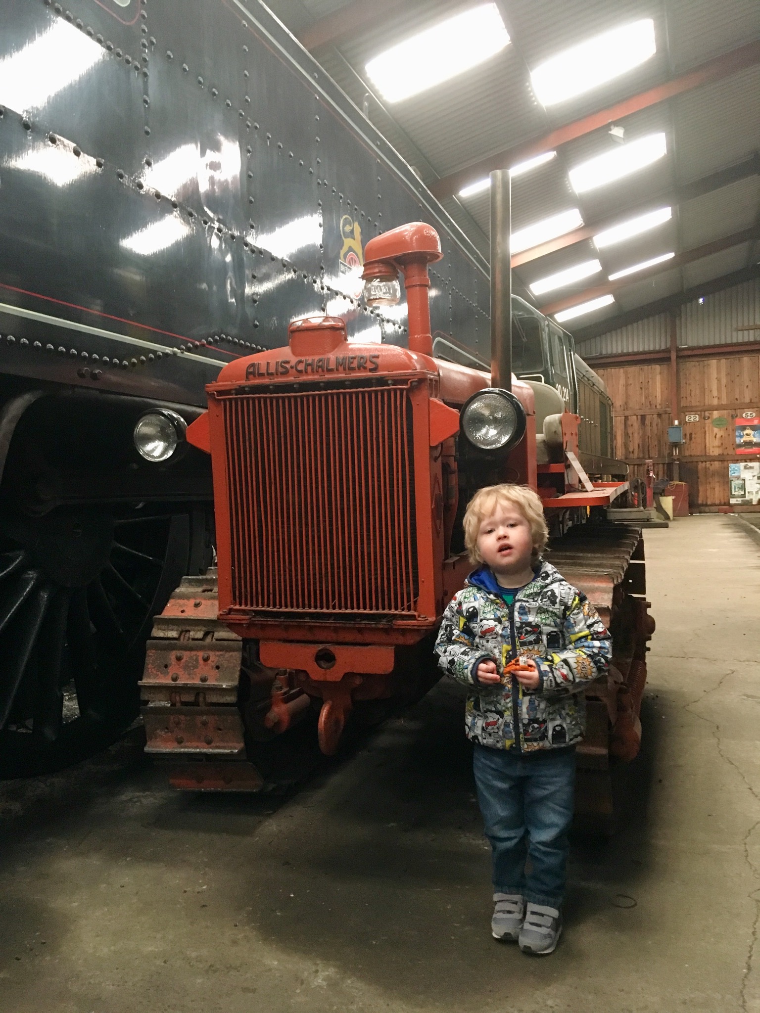 Lakeside and Haverthwaite Railway review Lucas standing next to an orange tractor in the sheds