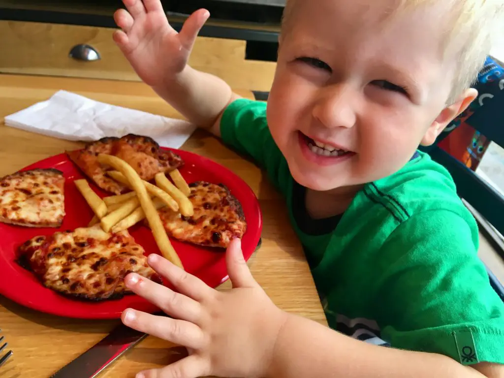 Epic Pizza’s at Pizza Hut Lucas smiling at the camera with pizza and chips in front of him