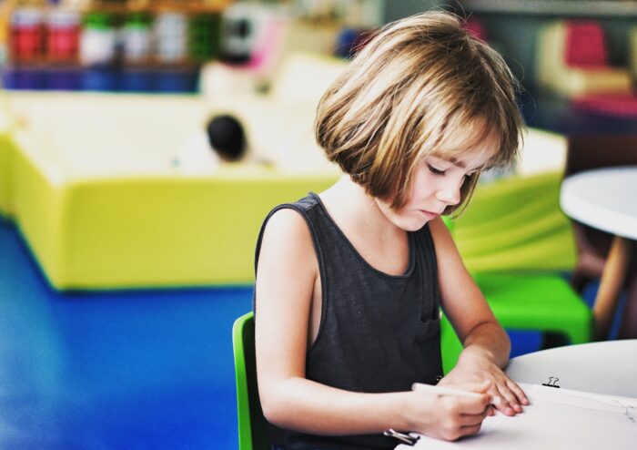 girl sat at a table writing