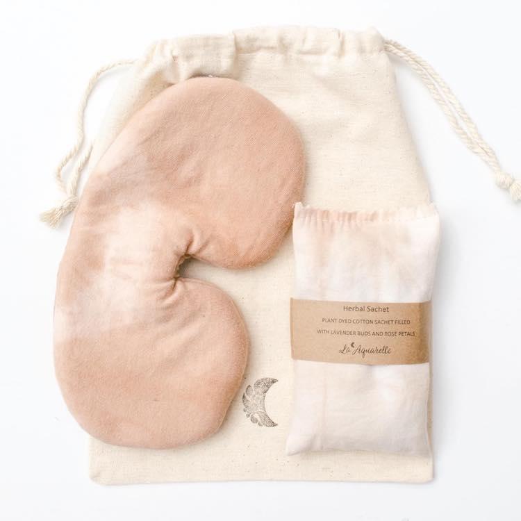 Women’s gift ideas a peach coloured sleep mask next to a cream bag of lavender 