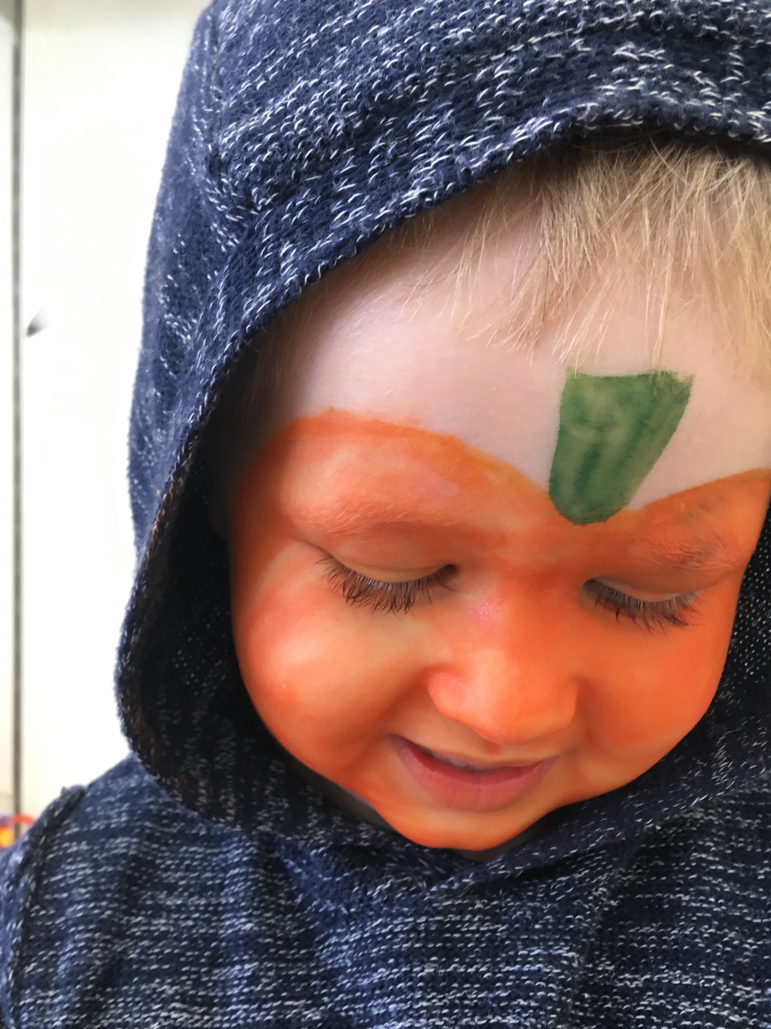 Lucas looking down smiling with pumpkin face paint on