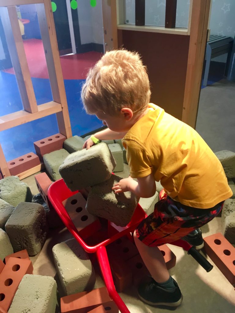 Lucas is is putting foam blocks into a red wheelbarrow 