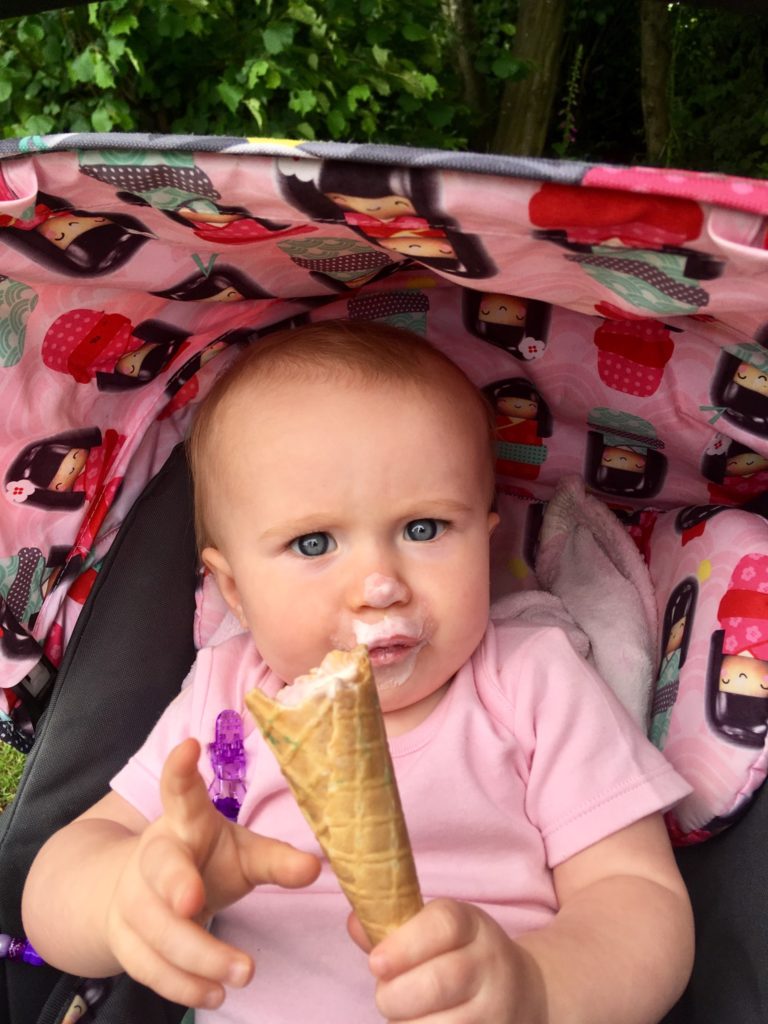 Baby girl in a pram holding an ice cream cone 