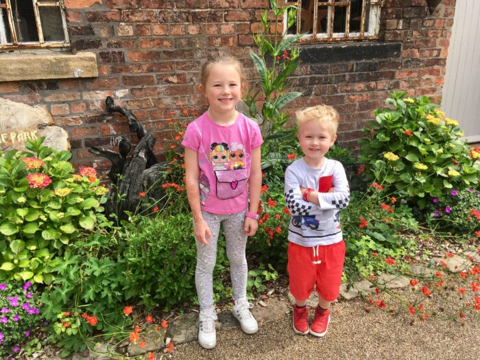 Lucas and his friends, a girl standing next to him in front of colourful flowers outside