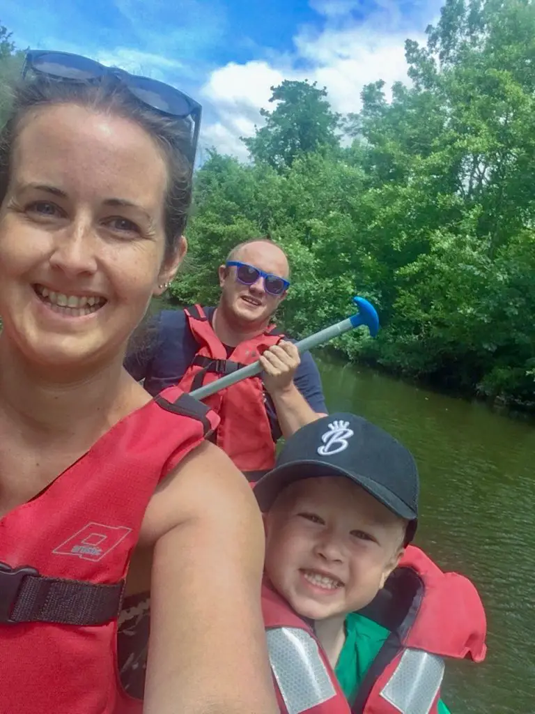 Is three looking at the camera smiling wearing life jackets in the canoe, you an see the river behind us