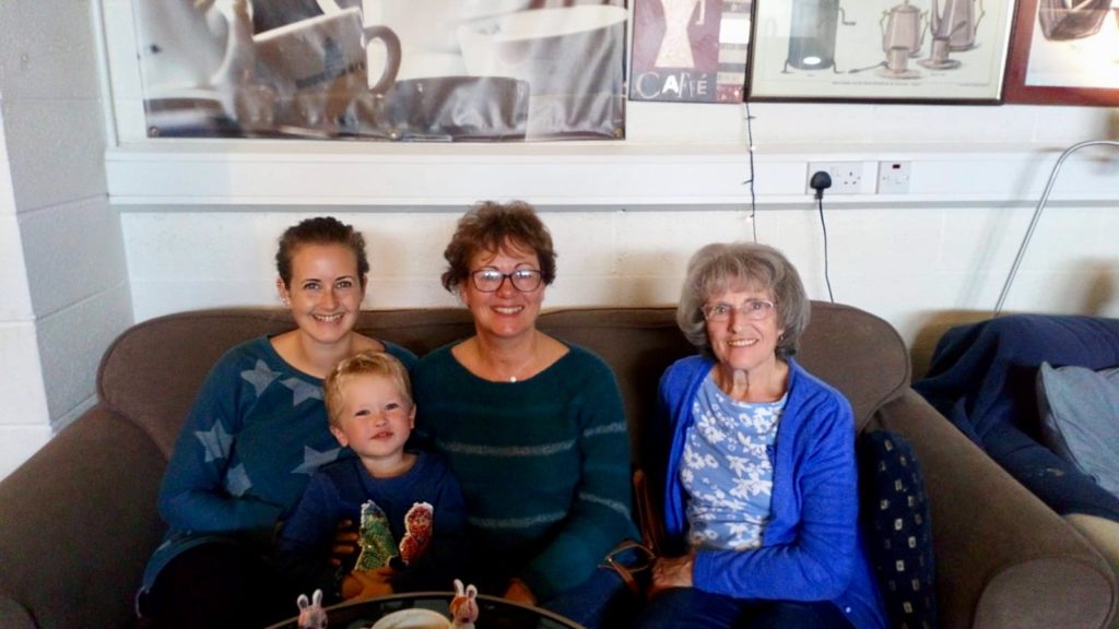 My mum, Grandma, lucas and I sat on a sofa smiling at the camera 