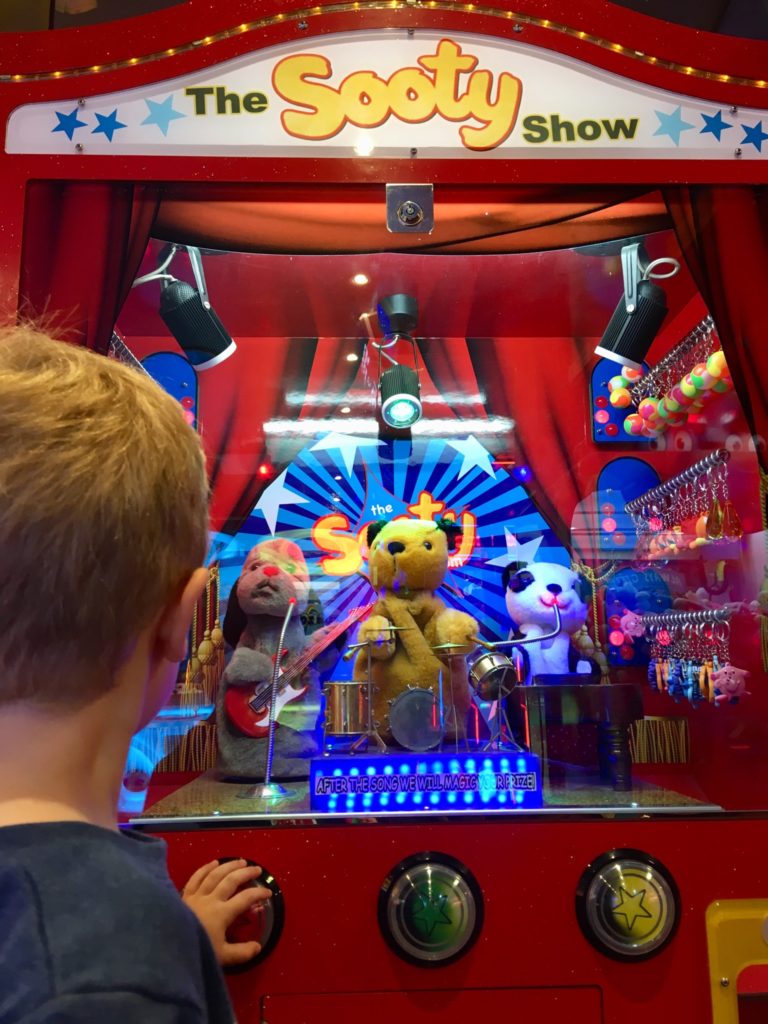 Lucas next to a sooty and sweep arcade machine 