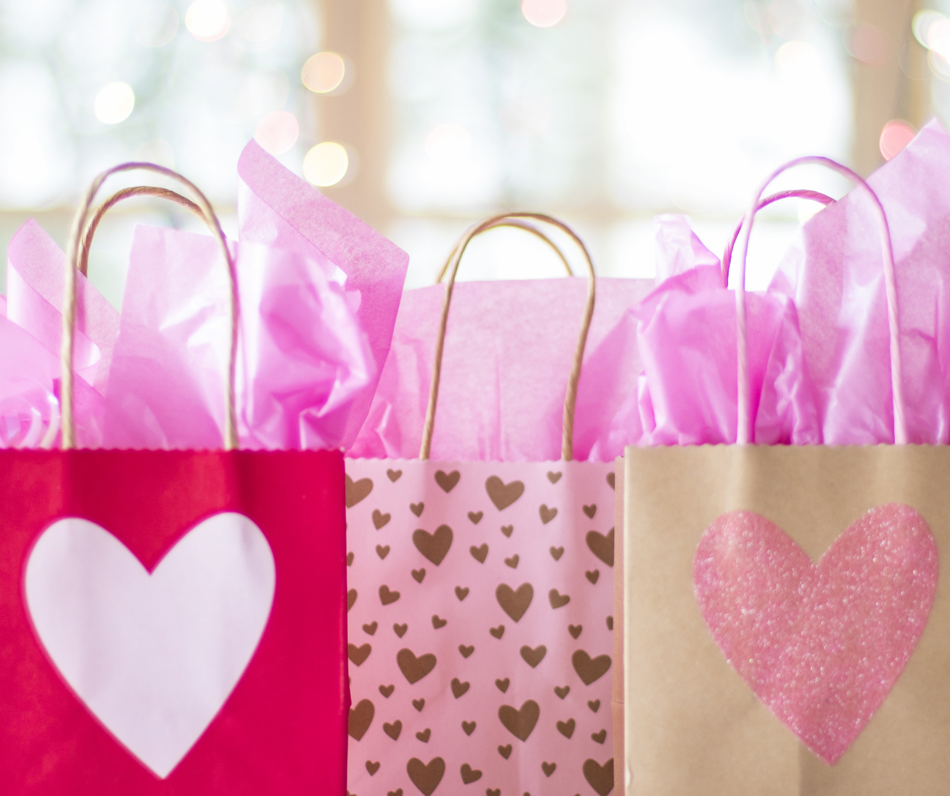 three gift bags with hearts on in a variety of pinks and golds
