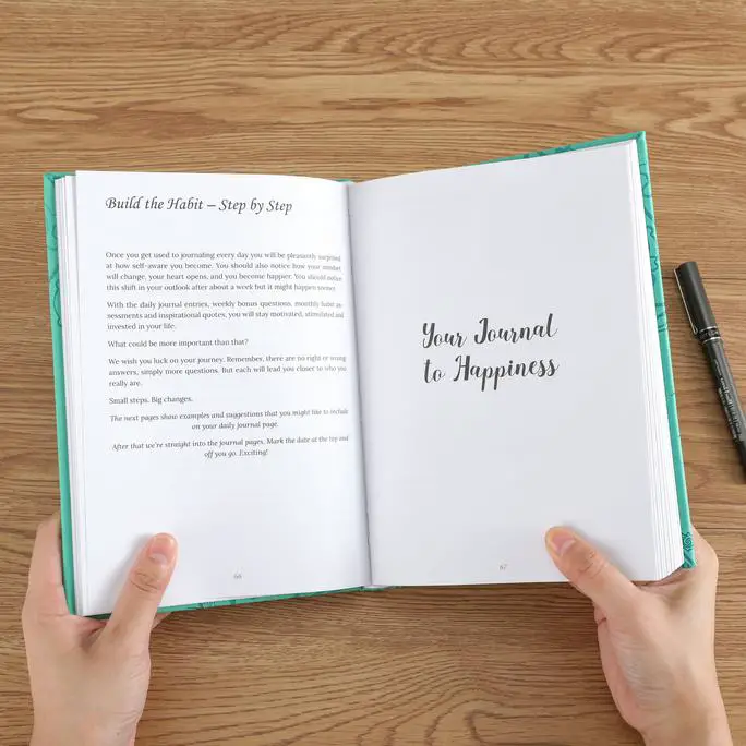 The happiness journal open with someone holding it