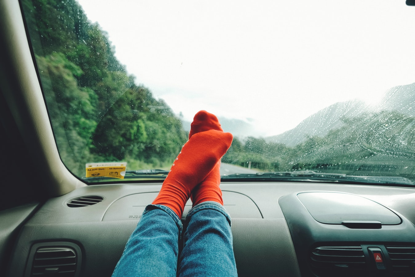 Must Have Road Trip Accessories. photo shows legs and feet resting on the dashboard with mountains in the distance