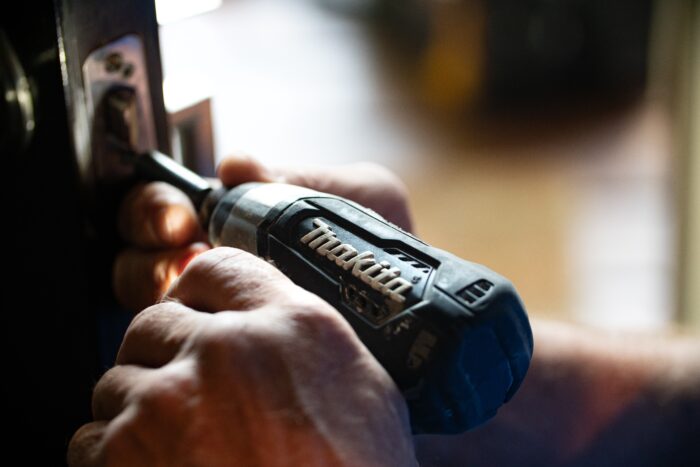 photo showing a hand using a drill into the side of a door