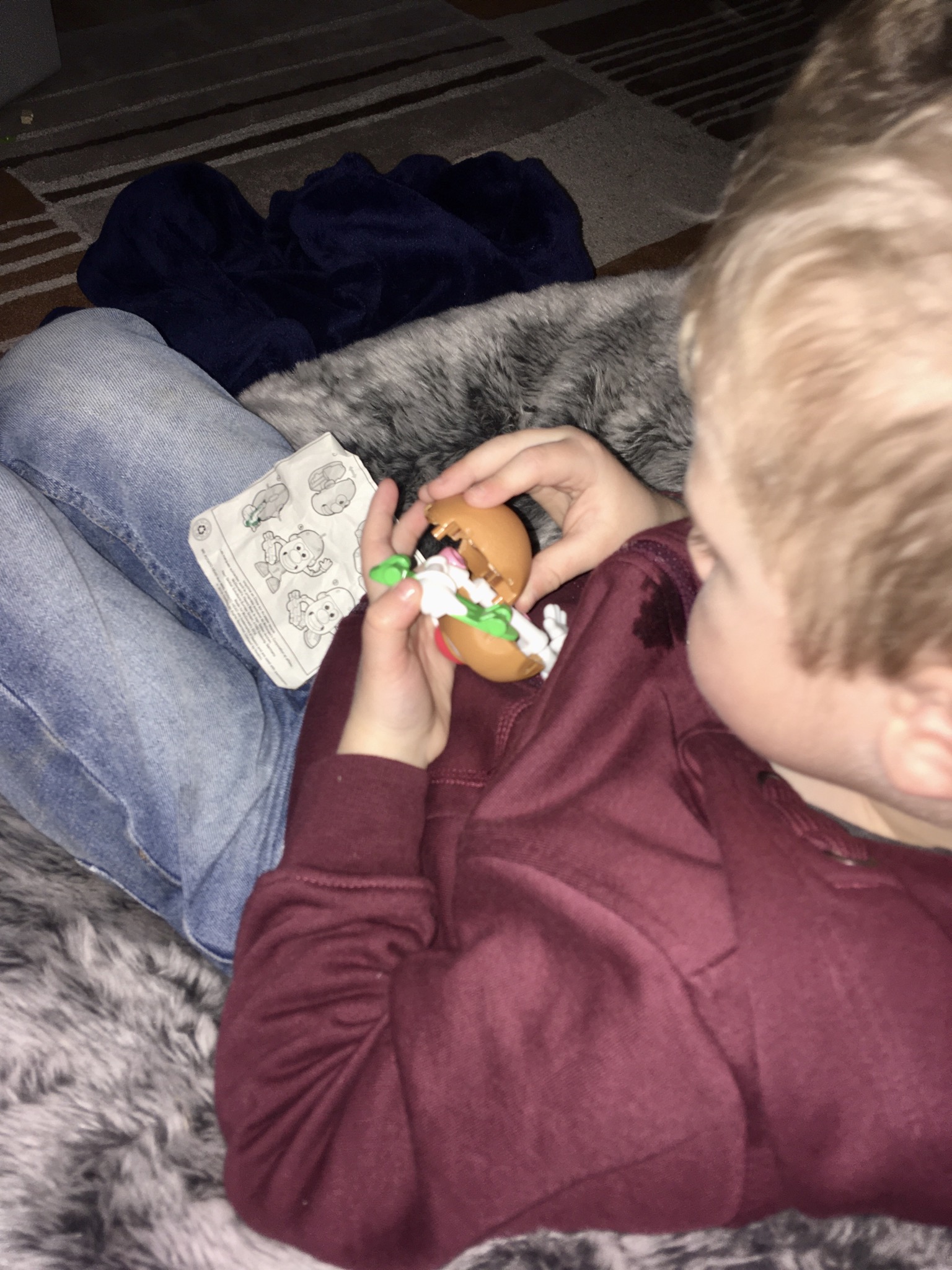 Lucas sat on a bean bag putting mr potato head together