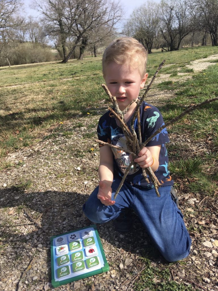 Lucas knelt down holding kindling he has collected 