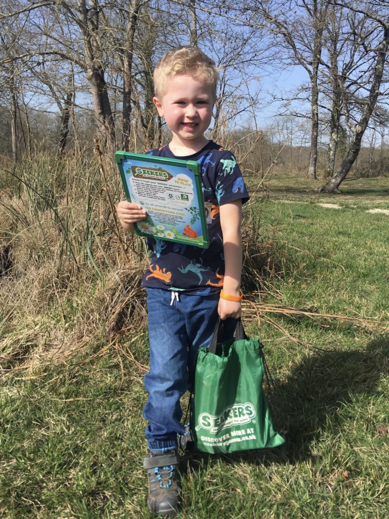 Lucas holding the magnetic scavenger hunt and the carry bag. He’s smiling looking at the camera 