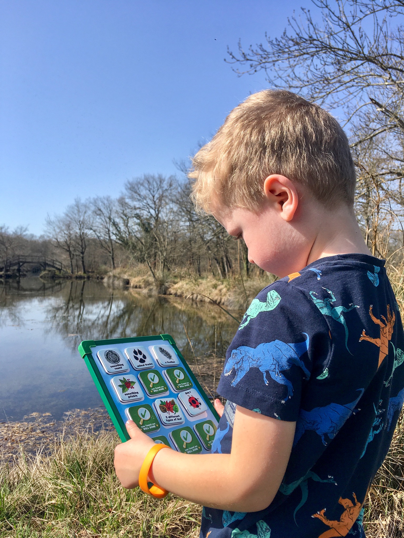 Lucas looking down at the seekers scavenger hunt board. You can see a lake in the background
