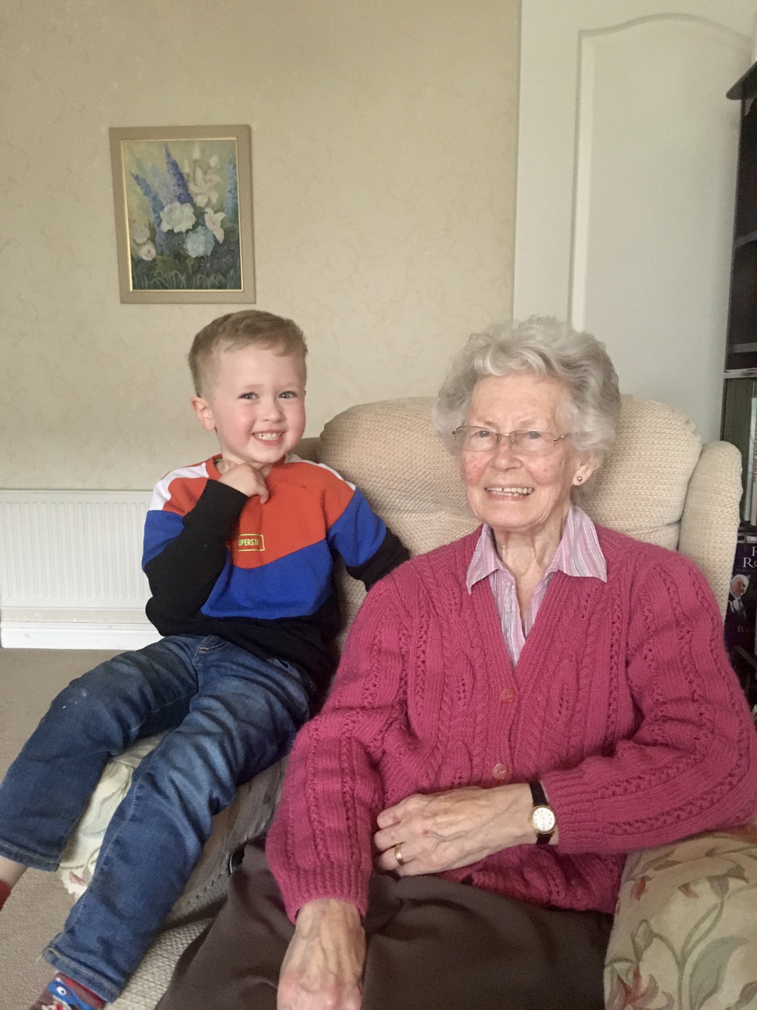 Lucas and his great grandma sat on the sofa looking at the camera
