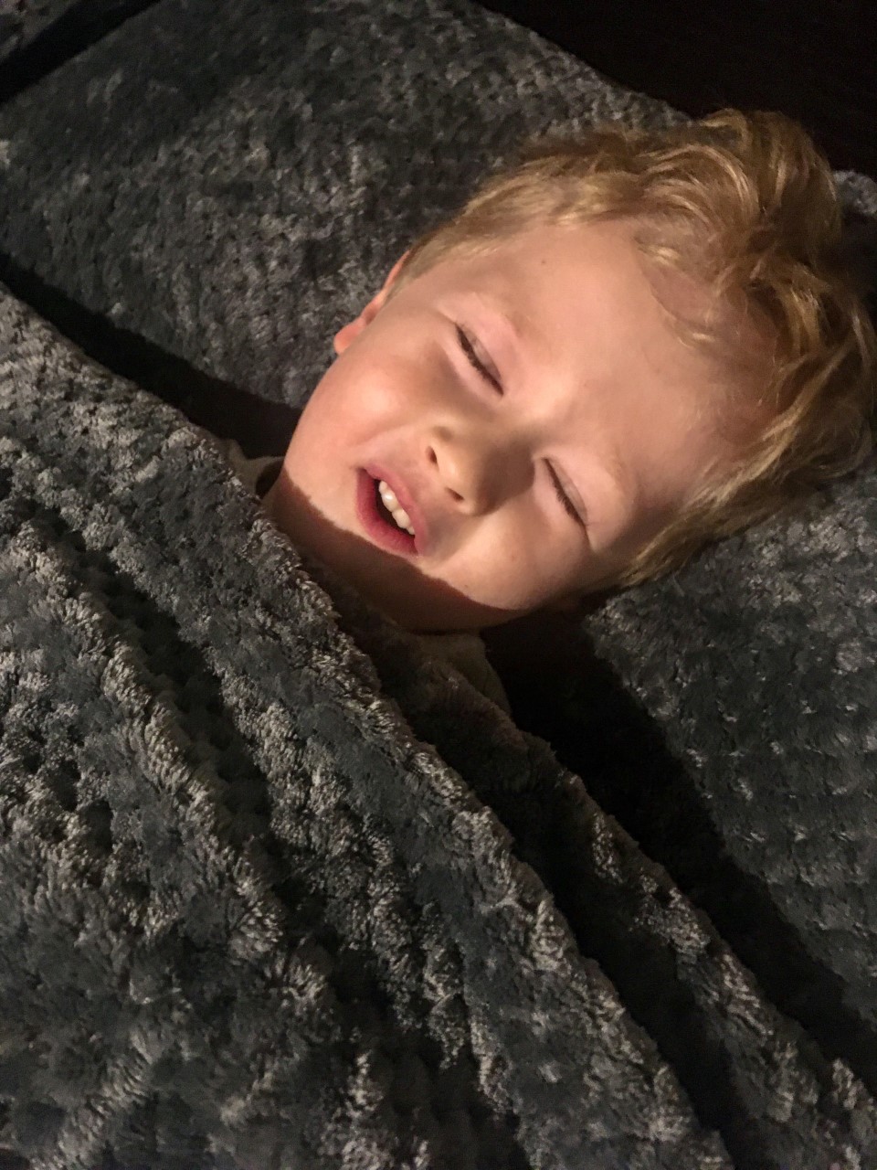 Lucas tucked up in bed with the grey waffle bedding on him