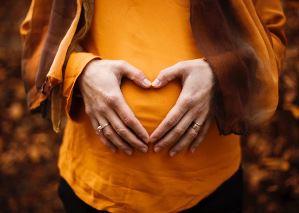 pregnant lady close up of belly with hands in heart shape