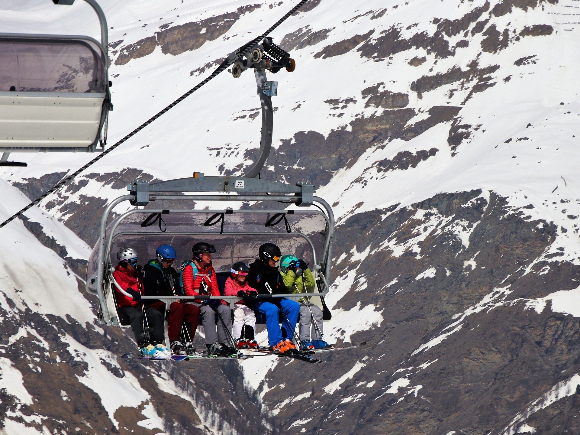 a cable car in the mountains showing a family of skiers sat down