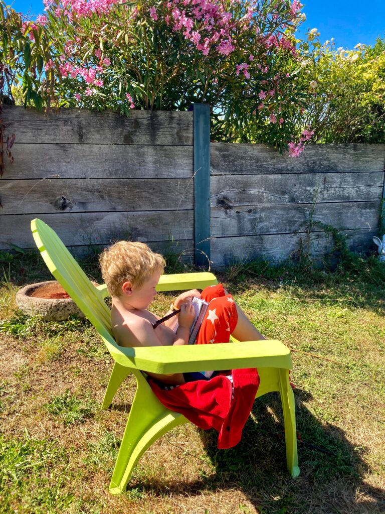 Lucas sat in the garden on a chair writing in his note book 