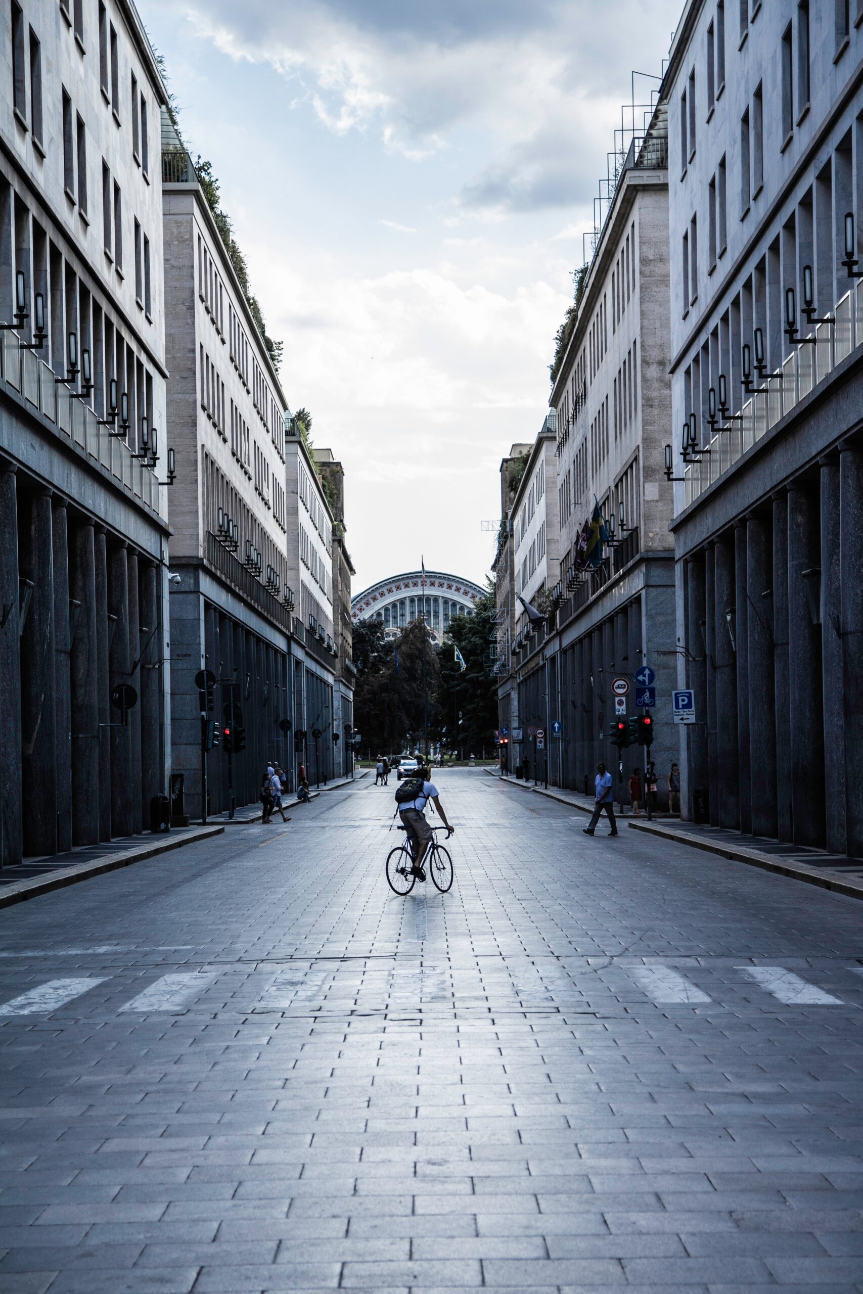 a man cycling along a path way in between buildings
