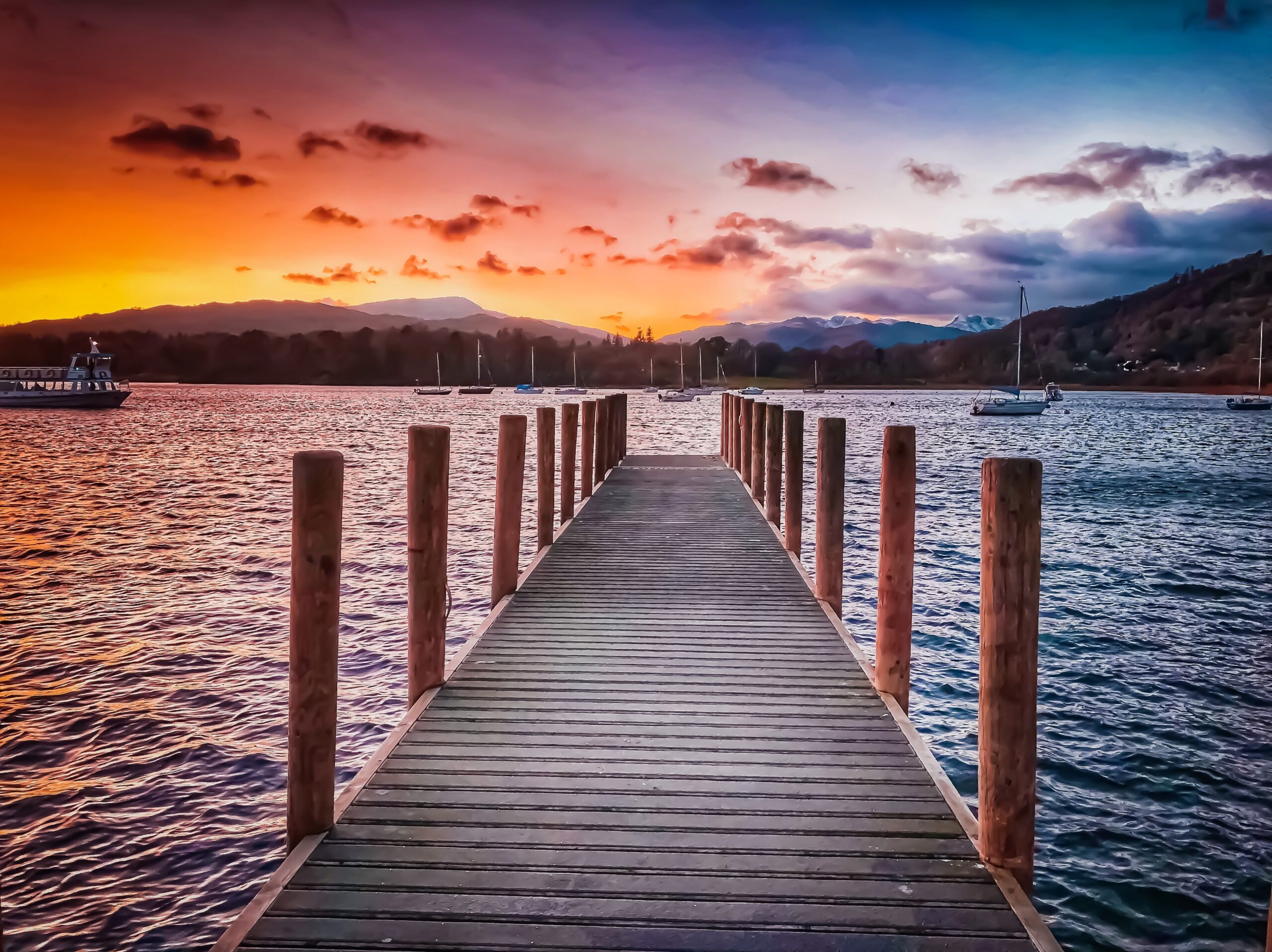 a pier on lake windermere with a sunset in the horizon
