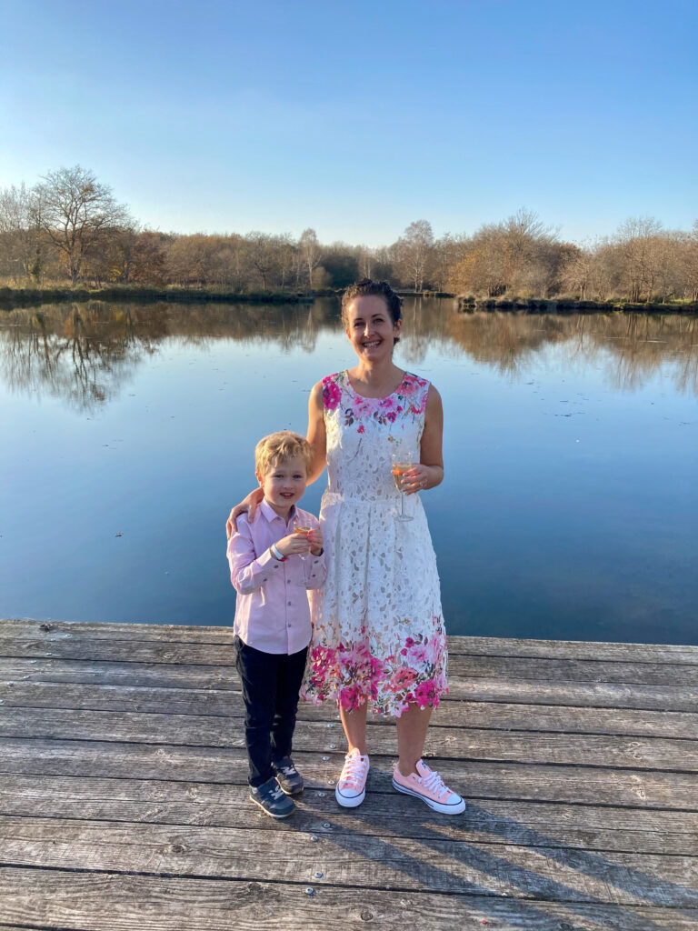 Lucas and I by the lake. I am wearing a white and pink floral yumi dress and pink converse trainers. Lucas is wearing navy trousers, a pink shirt and navy trainers