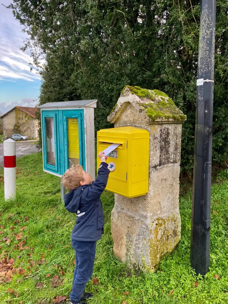 Lucas posting his letter to Pere Noel in a yellow post box 
