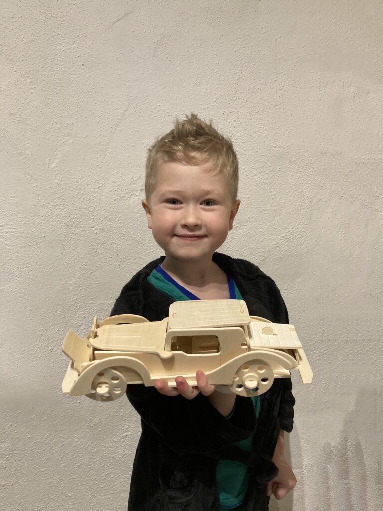 Lucas holding a wooden car he made 