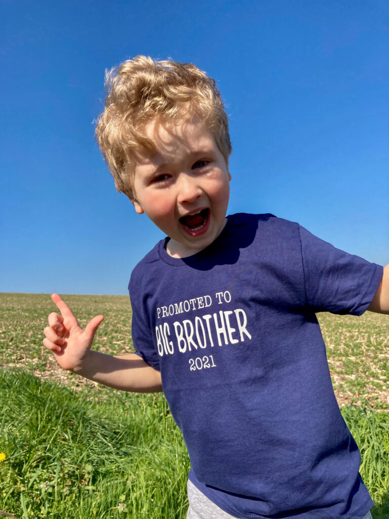 Lucas smiling with his mouth wide open wearing a navy Tshirt saying promoted to big brother 