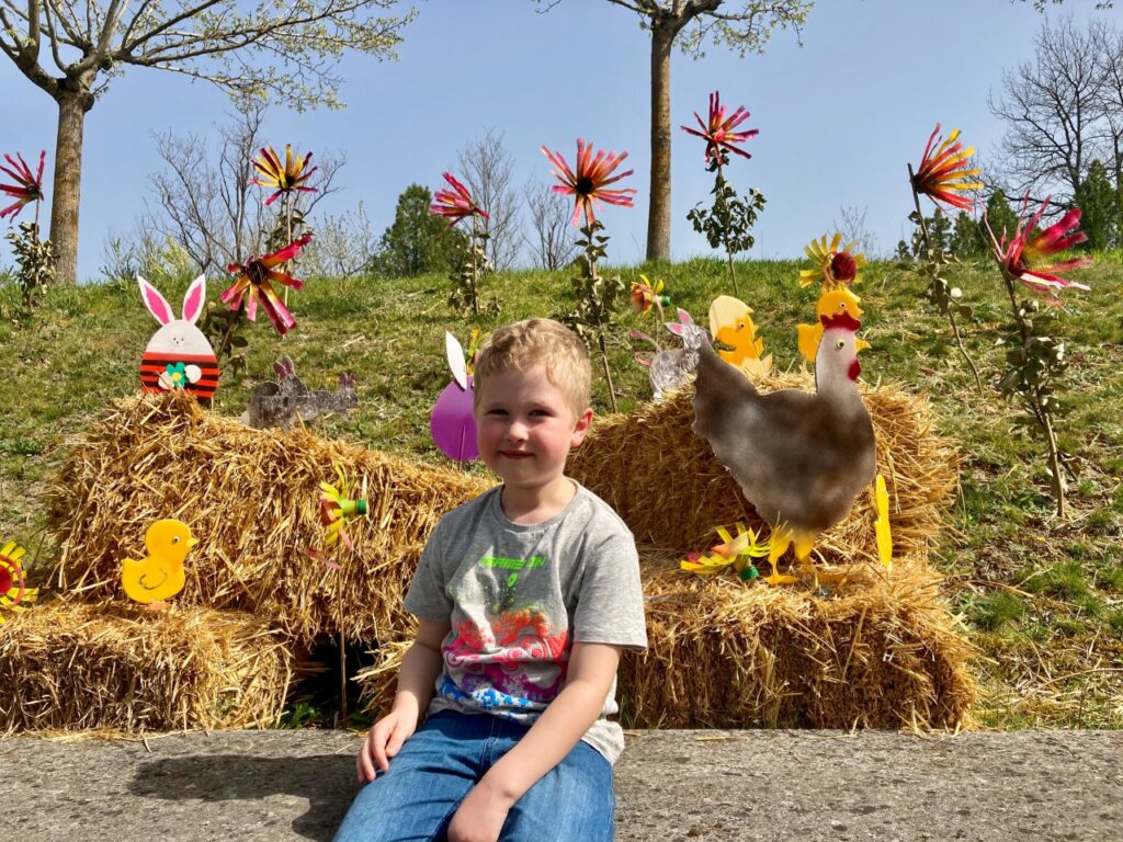 Lucas sat with hay bales and statues of flowers, chickens and bunnies behind him