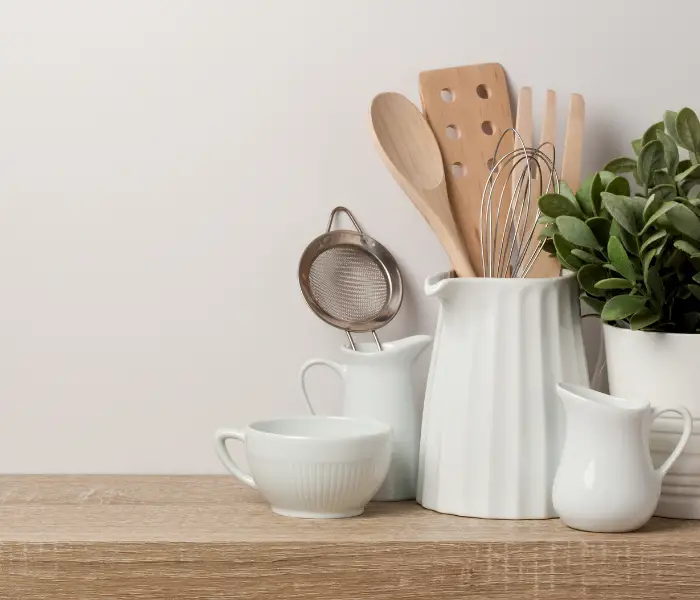 kitchen counter with white pots and jugs holding utensils