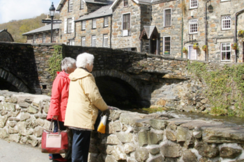 two senior ladies looking over a cobbled bridge