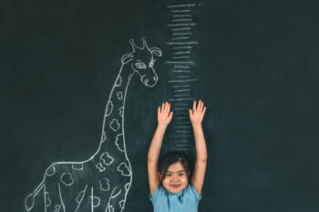 girl measuring herself against a growth chart on the wall