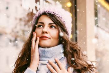 a lady with long dark hair wearing a hat and winter clothes. It is snowing