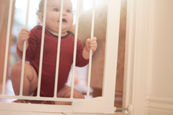 baby sitting behind a baby gate