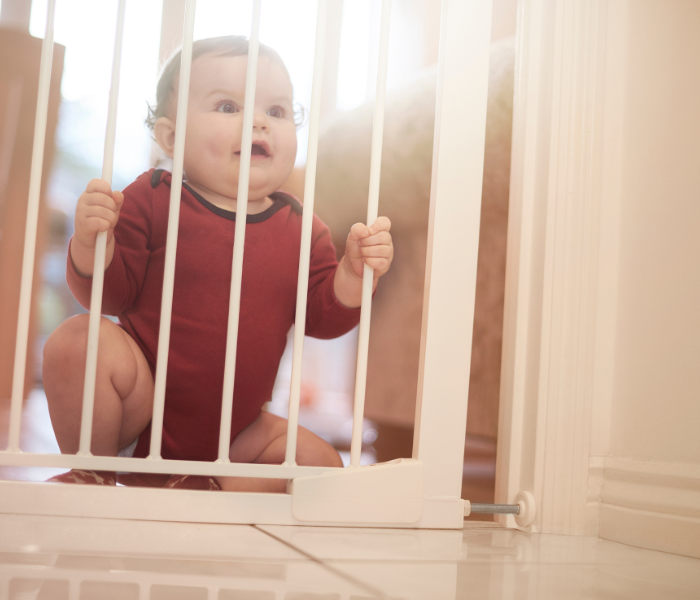 baby sitting behind a baby gate